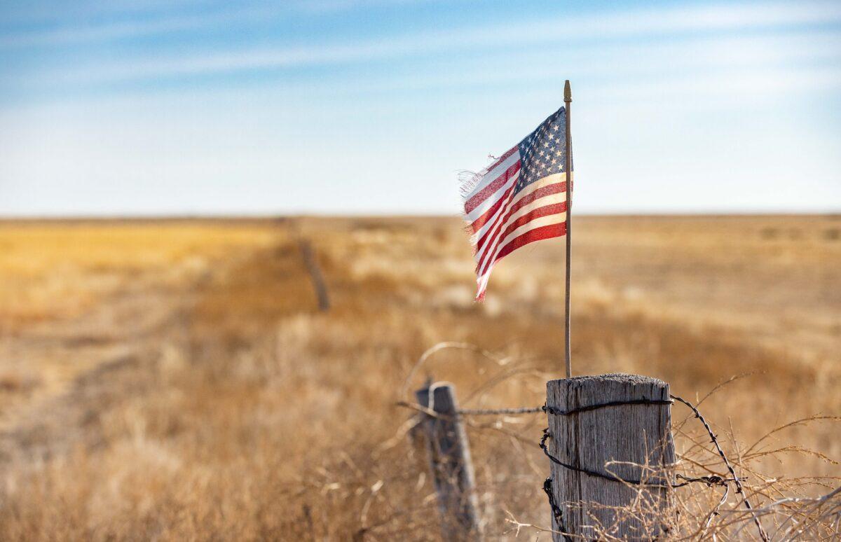 An American flag waves in the wind at the edge of a farm outside of Walsh, Colorado, on Dec. 6, 2021. (John Fredricks/The Epoch Times)