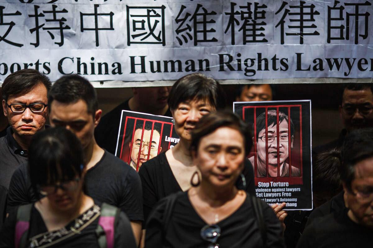 Portraits of detained Chinese human rights lawyers Jian Tianyong (L) and Wang Quanzhang are seen as Hong Kong pro-democracy activists observe a silent protest in support of human rights lawyers in China outside the Court of Final Appeal in Hong Kong's central district on July 9, 2017. (Tengku Bahar/AFP/Getty Images)