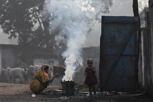 A woman along with her child burns coal for domestic use at Singrauli in Madhya Pradesh, India, on Nov. 18, 2021. (Money Sharma/AFP via Getty Images)