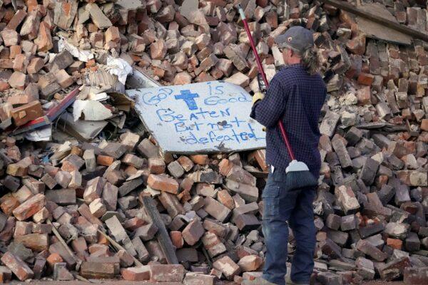 Rick Vincent, of Newaygo, Mich., reads a sign placed on a pile of building rubble as he stops work at the end of the day in Mayfield, Ky., on Dec. 12, 2021. (Mark Humphrey/AP Photo)