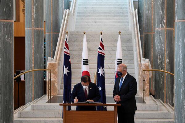 Australian Prime Minister Scott Morrison (R) looks on as South Korean President Moon Jae-in signs the official visitors book at Parliament House in Canberra, Australia, on Dec. 13, 2021. (Lukas Coch - Pool/Getty Images)