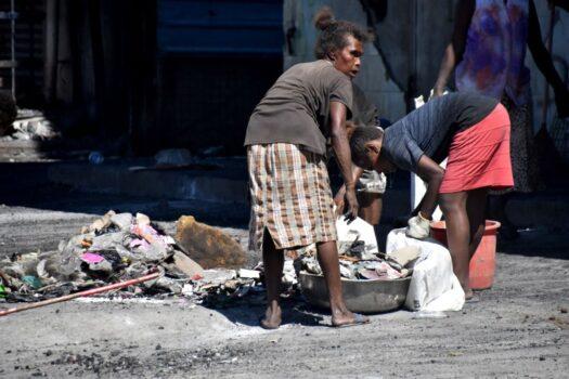 People clear debris from the streets in Chinatown in Honiara, Solomon Islands, on Nov. 28, 2021. (Charley Piringi/AFP via Getty Images)
