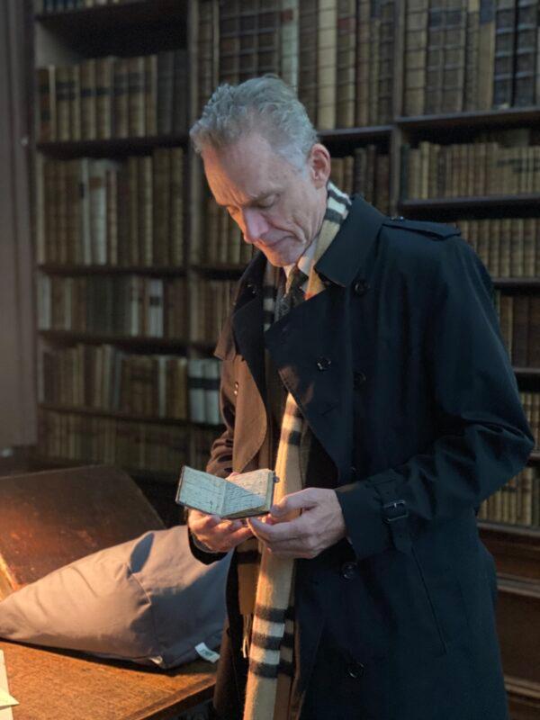 Jordan Peterson holds an Isaac Newton notebook in the Wren Library at Trinity College Cambridge in England on Nov. 20, 2021. (Courtesy of Jordan Peterson)