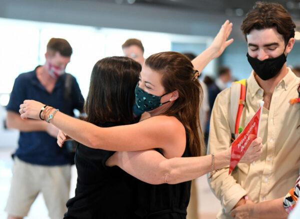 A couple reunite with family members after they arrived on the first flight from Sydney into Brisbane's domestic terminal since border restrictions have eased overnight in Brisbane, Australia, on Dec. 13, 2021. (Dan Peled/Getty Images)
