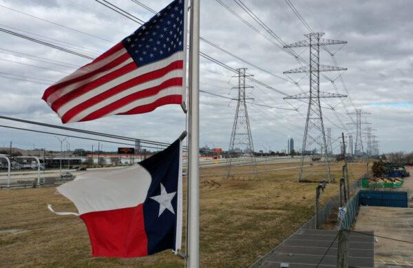 The U.S. and Texas flags fly in front of high voltage transmission towers on February 21, 2021 in Houston, Texas. (Justin Sullivan/Getty Images)