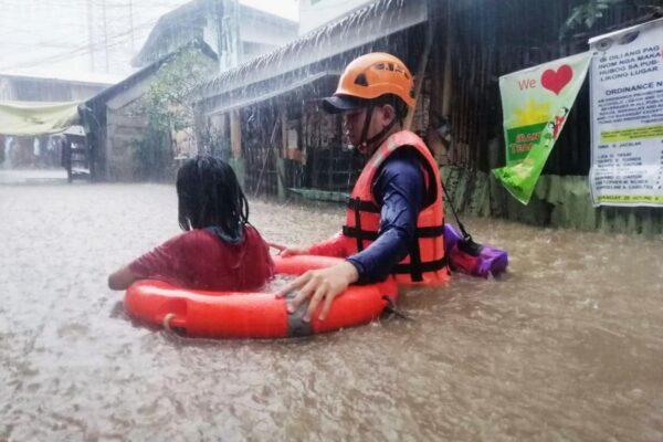 A rescuer assists a girl as they wade through flooding caused by Typhoon Rai in Cagayan de Oro City, southern Philippines, on Dec. 16, 2021. (Philippine Coast Guard via AP)