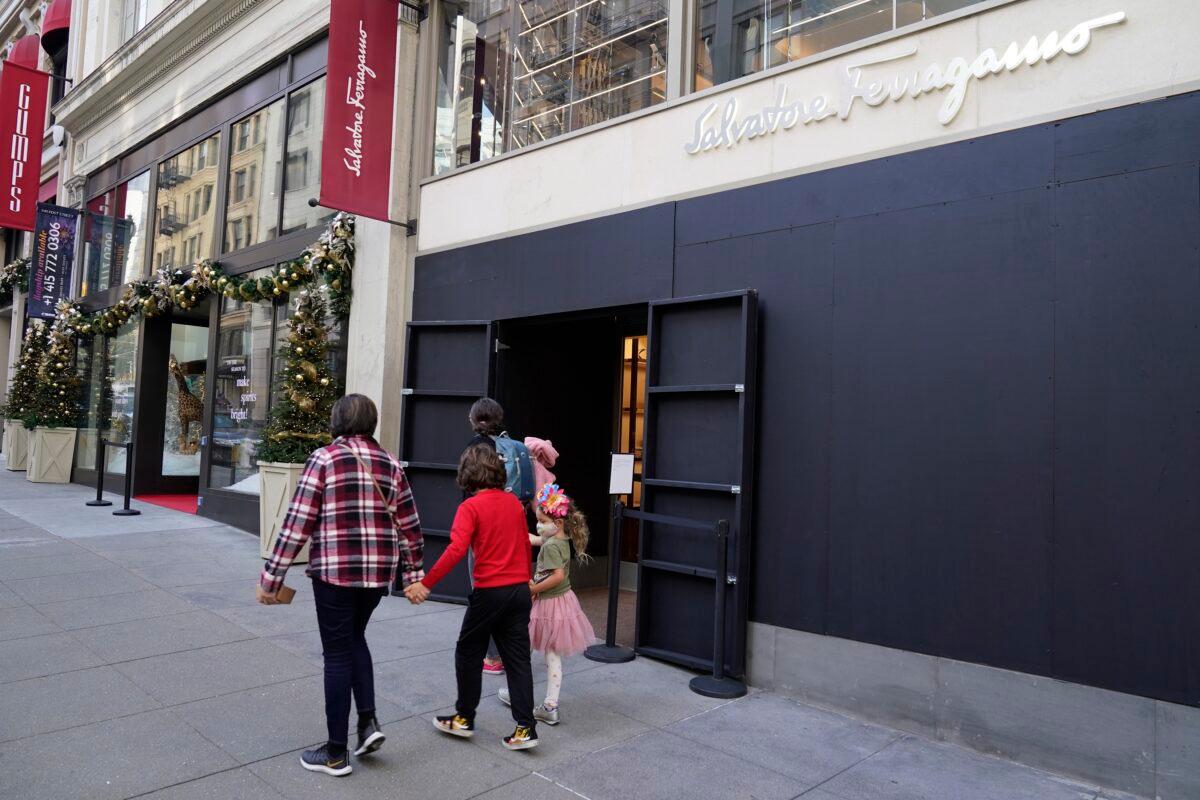 People walk past a boarded storefront window following recent robberies near Union Square in San Francisco on Dec. 2, 2021. (Eric Risberg/AP Photo)
