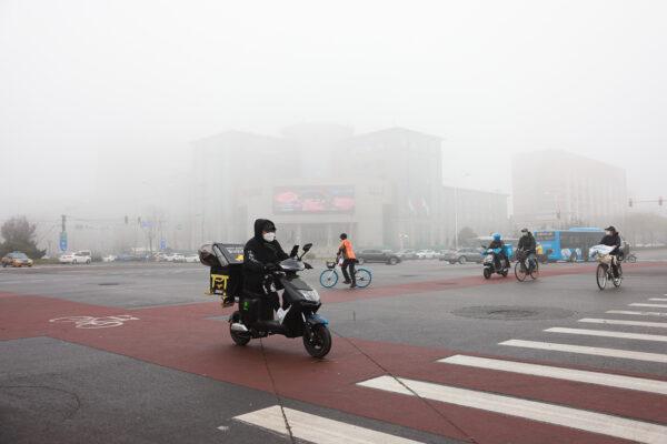 People wear masks as they travel along a street during smoggy weather in Beijing, China, on Nov. 18, 2021. (Lintao Zhang/Getty Images)