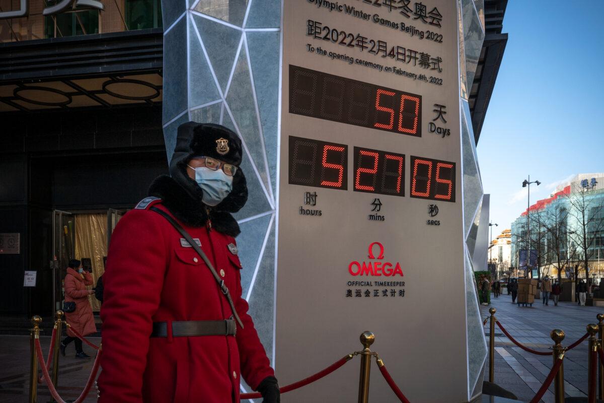 A security guard walks in front of a sign marking the countdown to the Beijing 2022 Winter Olympics in Beijing, China, on Dec. 16, 2021. (Andrea Verdelli/Getty Images)