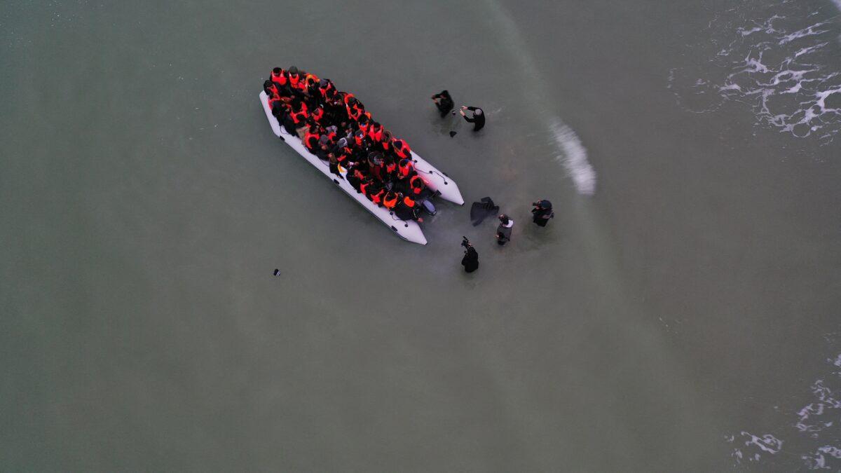 A drone photo shows a group of illegal immigrants as they get on an inflatable dinghy to leave the coast of northern France and to cross the English Channel, in Wimereux near Calais, France, on Dec. 16, 2021. (Pascal Rossignol/Reuters)