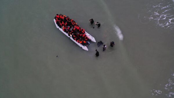 A drone photo showing a group of illegal immigrants react as they succeeded to get on an inflatable dinghy, to leave the coast of northern France and to cross the English Channel, in Wimereux near Calais, France, on Dec. 16, 2021. (Pascal Rossignol/Reuters)