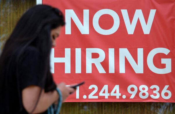 A woman walks by a "Now Hiring" sign outside a store in Arlington, Va., on Aug. 16, 2021. (Olivier Douliery/AFP via Getty Images)