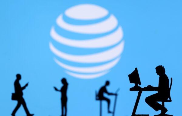 Small toy figures with laptops and smartphones are seen in front of a displayed AT&T logo, in this illustration taken on Dec. 5, 2021. (Dado Ruvic/Illustration/Reuters)