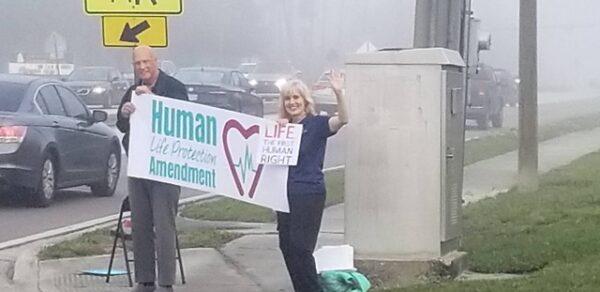 Ken and Lori, parishioners of Holy Family Catholic Church in Orlando, Fla., promote the Human Life Protection Amendment citizen initiative to commuters during morning rush hour on Dec. 8, 2021. (Mark Minck)
