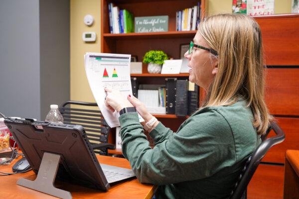 Julie Kraemer looks at improved test scores of high school students for the first half of the school year in her office in Hutsonville, Ill., on Dec. 17, 2021. (Cara Ding/The Epoch Times)