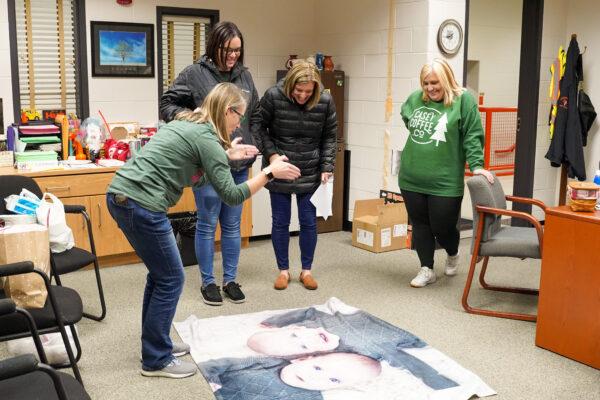 Julie Kraemer describes the size of her newborn twin grandkids to her staff in her school office in Hutsonville, Ill., on Dec. 17, 2021. (Cara Ding/The Epoch Times)