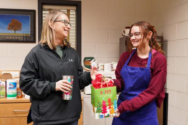 A student hand-delivers a Christmas gift to Julie Kraemer in her office at Hutsonville public school district in Hutsonville, Ill., on Dec 17, 2021. (Cara Ding/The Epoch Times)