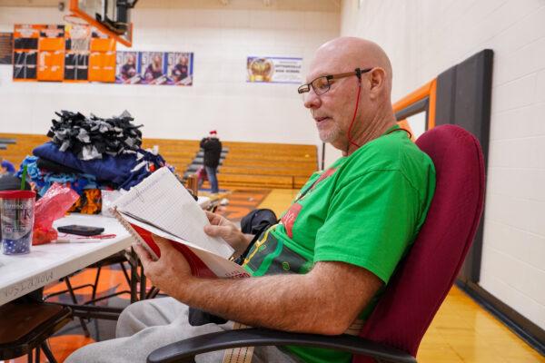 Physical education teacher Randy Hawkins looks at the attendance records he kept this school year in Hutsonville High School gym in Hutsonville, Ill., on Dec. 17, 2021. (Cara Ding/The Epoch Times)