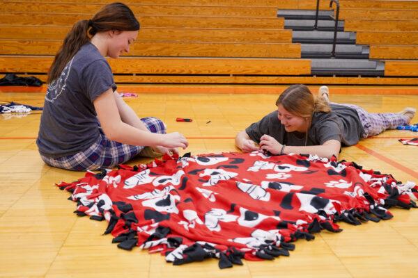 Ilayan Sheets (L) makes a blanket for sick children at local hospitals with a school friend on the last school day before the holiday season on Dec. 17, 2021. (Cara Ding/The Epoch Times)