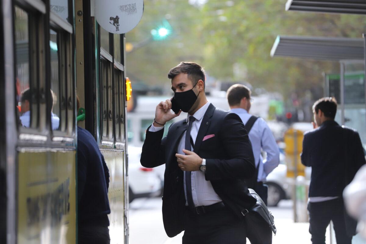 An office worker getting on a tram at Collins Street in Melbourne, Australia, on April 15, 2021. (AAP Image/Diego Fedele)