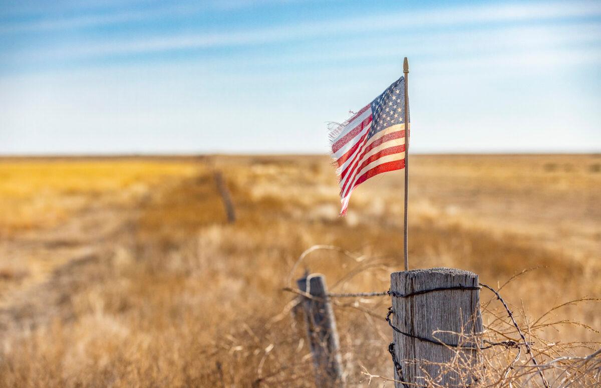 An American flag waves in the wind at the edge of a farm outside of Walsh, Colo., on Dec. 6, 2021. (John Fredricks/The Epoch Times)