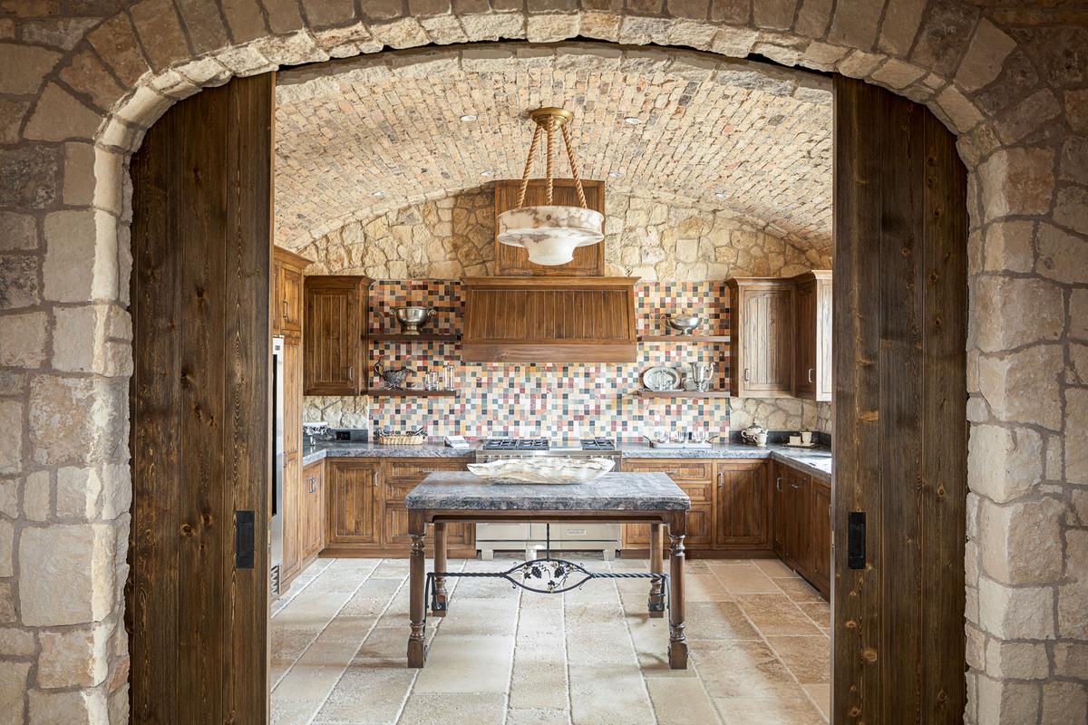 The wine cellar’s kitchen glows with the use of fine wood, polished stone, and classy accents. (Matthew Walla/Jade Mills)
