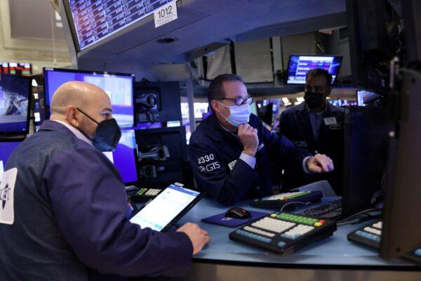 Traders wearing face masks work on the trading floor at the New York Stock Exchange (NYSE) as the Omicron coronavirus variant continues to spread in Manhattan, New York City, U.S. on Dec. 20, 2021. (Andrew Kelly/Reuters)