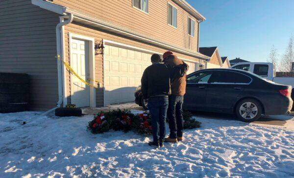 Two friends of seven people whose bodies were found in a Moorhead, Minn., home comfort each other next to seven wreaths that were left outside the residence, Minn., on Dec. 20, 2021. (Dave Kolpack/AP Photo)