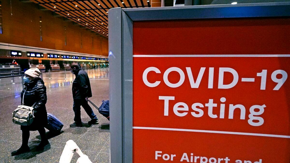 Travelers pass a sign near a COVID-19 testing site in Terminal E at Logan Airport in Boston, on Dec. 21, 2021. (Charles Krupa/AP Photo)