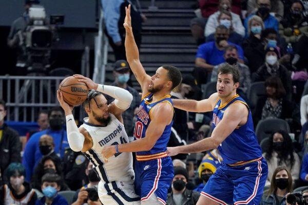 Memphis Grizzlies forward Dillon Brooks (L) is defended by Golden State Warriors guard Stephen Curry, middle, and forward Nemanja Bjelica during the first half of an NBA basketball game in San Francisco on Dec. 23, 2021. (Jeff Chiu/AP Photo)