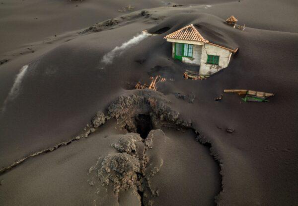A fissure is seen next to a house covered with ash on the Canary island of La Palma, Spain, on Dec. 1, 2021. (Emilio Morenatti/AP Photo)