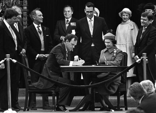 Attorney General Jean Chretien signs the proclamation repatriating Canada's constitution while Queen Elizabeth II watches, in Ottawa on April 17, 1982. Prime Minister Pierre Trudeau is standing behind Chretien. (The Canadian Press/Ron Poling)