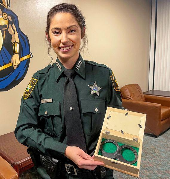 Katherine Shoulta with her late father's original handcuffs. (Courtesy of <a href="https://www.facebook.com/pinellassheriff">Pinellas County Sheriff's Office</a>)