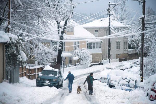 Residents navigate Broad Street in the snow in Nevada County, Calif., on Dec. 27, 2021. (Elias Funez/The Union via AP)