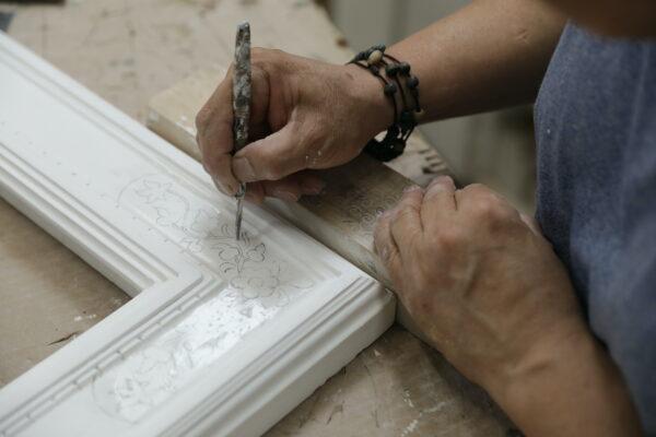 A craftsperson works on etching a pattern on a frame. (Lux Aeterna Photography)