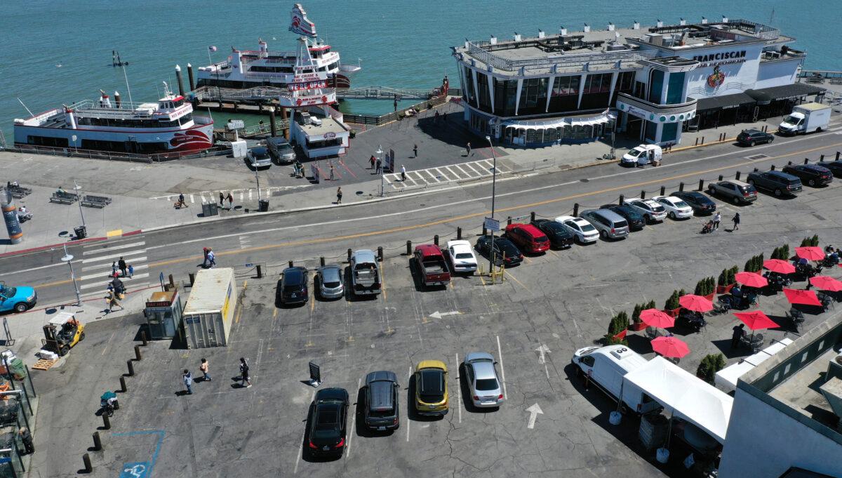 Cars and tables fill a parking lot next to a restaurant and bay cruise terminal at the Fisherman's Wharf tourist destination in San Francisco on June 14, 2021. (Justin Sullivan/Getty Images)