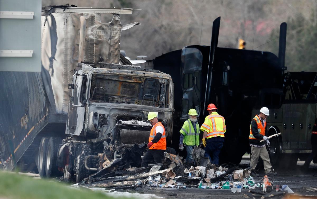 Workers clear debris from the eastbound lanes of Interstate 70 on April 26, 2019, in Lakewood, Colo., following a deadly pileup involving a semi-truck hauling lumber. Rogel Aguilera-Mederos, the trucker who was convicted of causing the fiery pileup that killed four people and injured six others, was sentenced on Dec. 13, 2021, to 110 years in prison. (David Zalubowski/AP Photo, File)