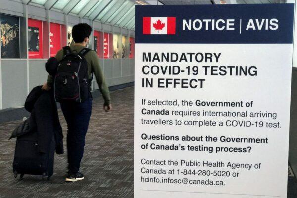 A traveler walks past a "Mandatory COVID-19 Testing" sign at Pearson International Airport, in Toronto, Ontario, on Dec. 18, 2021. (Carlo Allegri/Reuters)