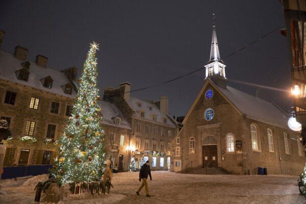 A lone man walks through a deserted Place Royale in Quebec City on New Year’s Eve, when the provincial government’s nightly curfew from 10 p.m. to 5 a.m. came into effect, Dec. 31, 2021. (The Canadian Press/Jacques Boissinot)