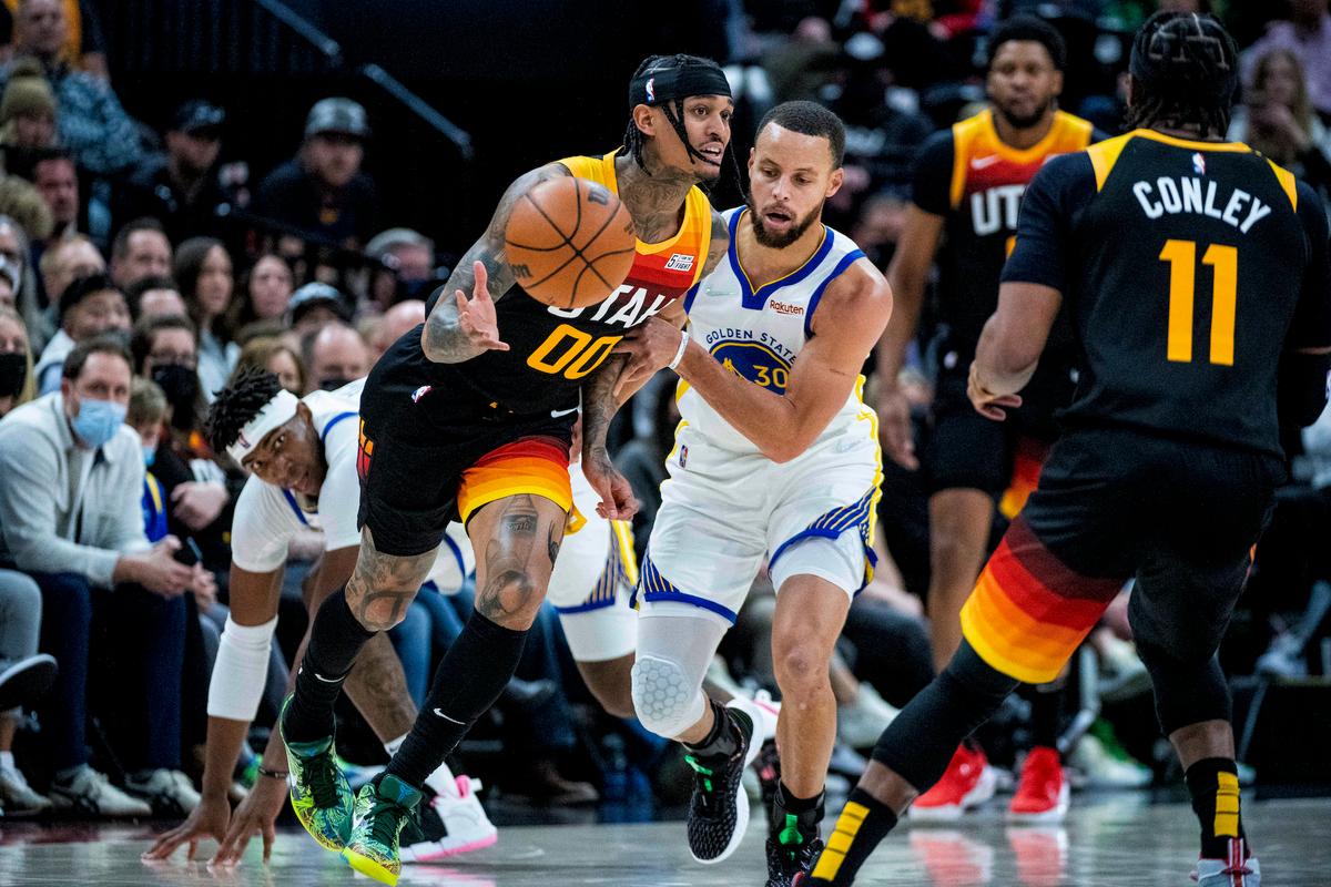 Utah Jazz guard Jordan Clarkson (00) passes the ball to Utah Jazz guard Mike Conley (11) while Clarkson is guarded by Golden State Warriors guard Stephen Curry (30) in the first half during an NBA basketball game in Salt Lake City, on Jan. 1, 2022. (Isaac Hale/AP Photo)