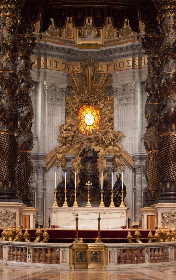 The Baldacchino is framed by twisting columns that draw the eye through to the Cathedra of Petri (Throne of St. Peter). As the sun sets, golden light shines through the oval window and is extended with sculpted shafts of golden light. Cherubs float in a divine cloud that seems to frame the bronze Throne of Peter. (J.H.Smith/Cartio)