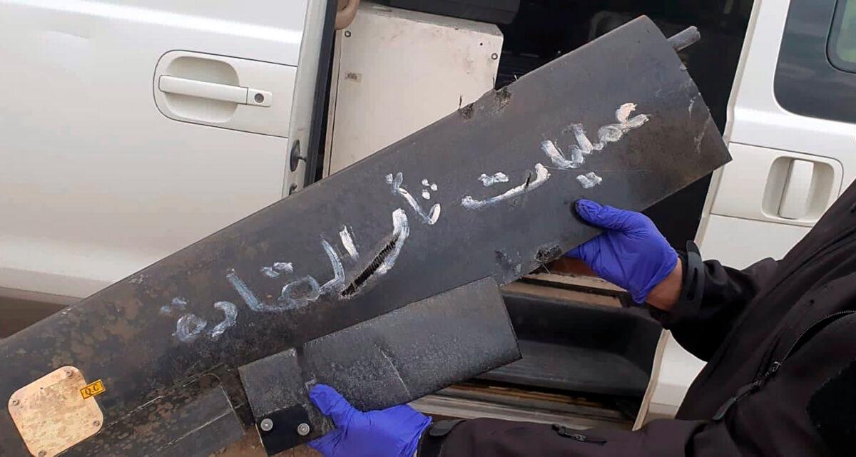 A security official holds part of the wreckage of a drone with Arabic that reads, "revenge operations for our leaders," at Baghdad airport, Iraq, on Jan. 3, 2022. (International Coalition via AP)