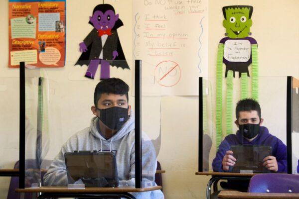 Students sit behind barriers and use tablets during an in-person English class at St. Anthony Catholic High School during the COVID-19 pandemic on March 24, 2021, in Long Beach, Calif. (Patrick T. Fallon/AFP via Getty Images)