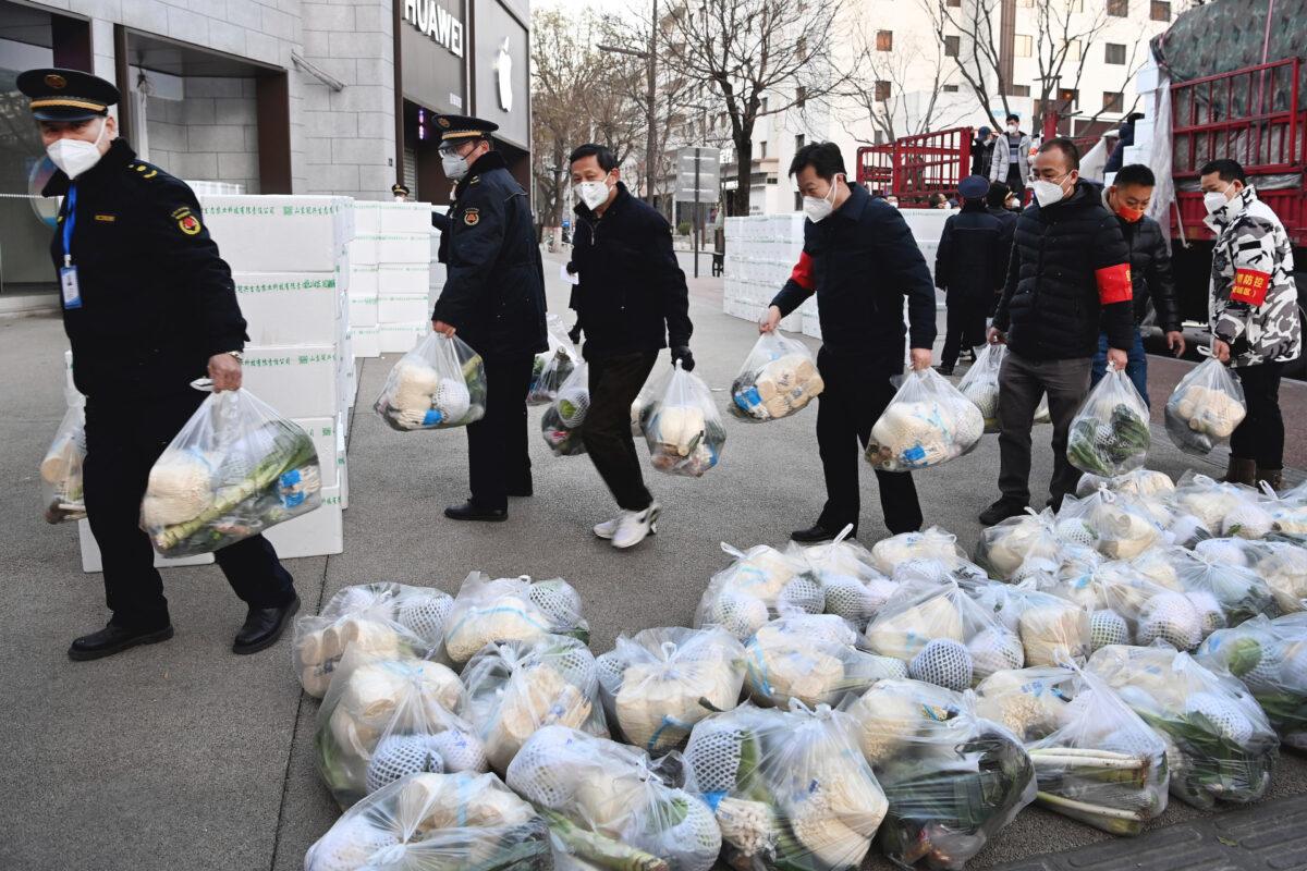 Subdistrict office staff carry daily necessities to be delivered to households under closed-off management in Xi'an, in northwestern China's Shaanxi Province, on Dec. 29, 2021. (Liu Xiao/Xinhua via AP)