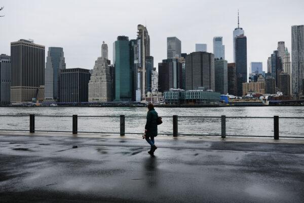 People walk in Brooklyn while lower Manhattan looms in the background in New York on March 28, 2020. (Spencer Platt/Getty Images)