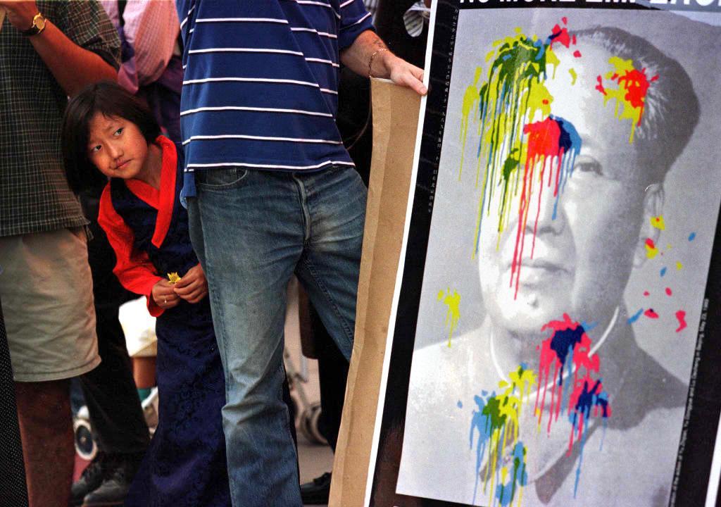 A 6-year-old from Tibet peers through anti-China protesters toward a paint-splattered portrait of former Chinese communist leader Mao Zedong in Los Angeles on Nov. 2, 1997. (Mike Nelson/AFP via Getty Images)