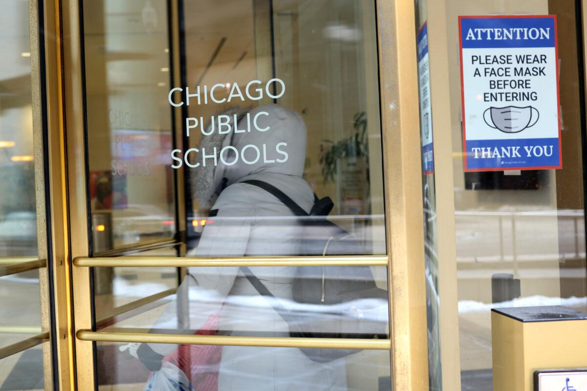 A sign requesting the wearing of a "face mask before entering" is displayed at the entrance of the headquarters for Chicago Public Schools in Chicago on Jan. 5, 2022. (Scott Olson/Getty Images)