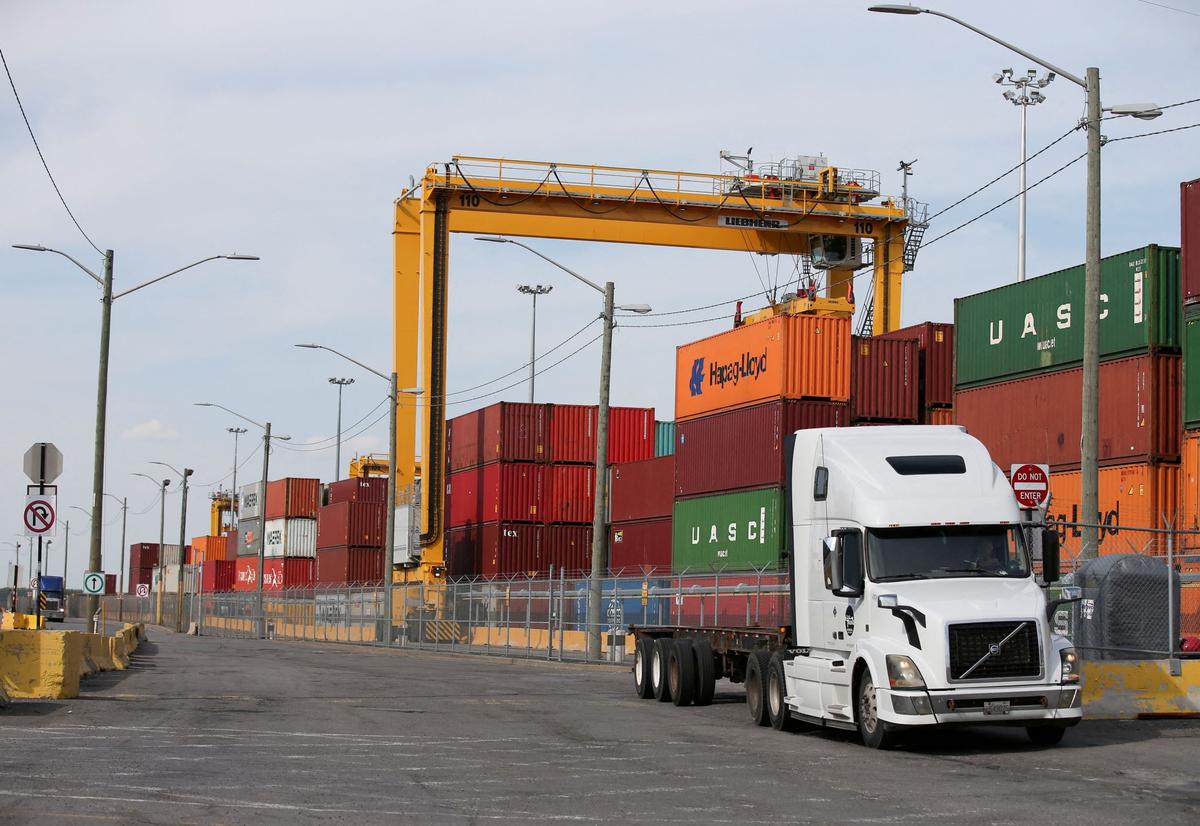 A truck moves past stacked shipping containers at the Port of Montreal in Montreal, Quebec, Canada, on May 17, 2021. (Christinne Muschi/Reuters)