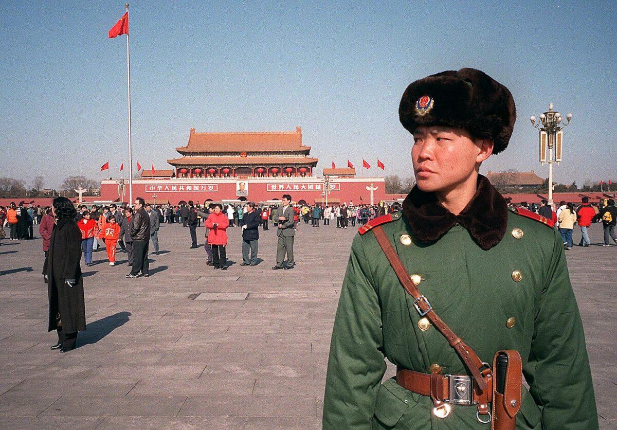 A Chinese military policeman keeps a look-out for Falun Gong adherents to stop them from handing out information brochures exposing the CCP's persecution of their faith at Tiananmen Square in Beijing, China, on Feb. 6, 2000. (Stephen Shaver/AFP via Getty Images)
