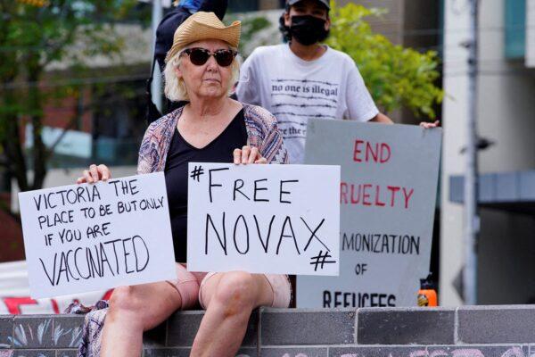 A protestor holds signs outside the Park Hotel, where Serbian tennis player Novak Djokovic is believed to be living, in Melbourne, Australia, on Jan. 6, 2022. (Sandra Sanders/Reuters)